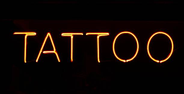 istock tattoo - reads the yellow glowing neon sign 2228473620
