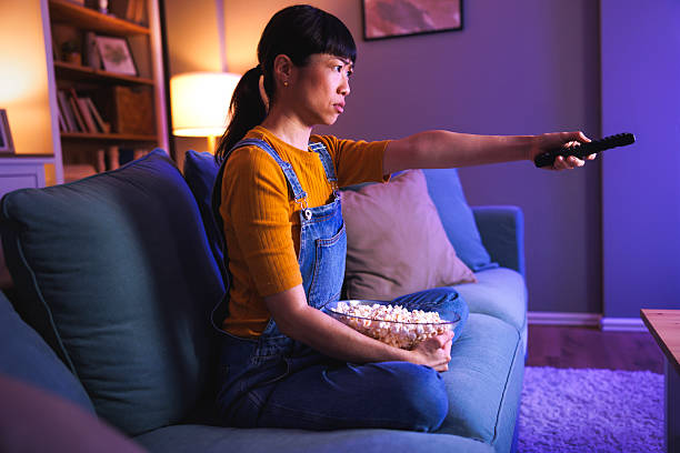 istock Serious woman watching TV at home late at night changing channels using remote control 2228475028