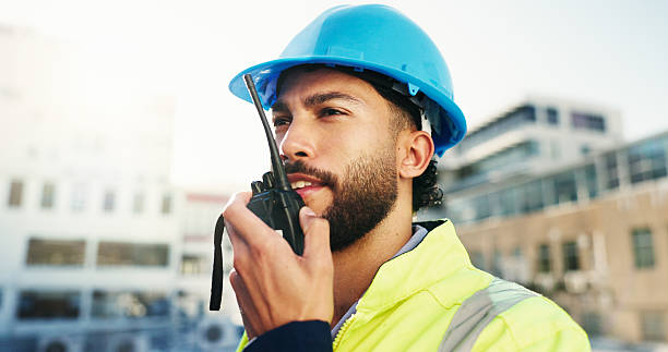 istock Construction site, radio and man with engineering, feedback and inspection with quality control. Helmet, outdoor and person with architecture, conversation and property renovation with safety check 2228476355