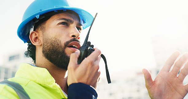 istock Construction site, radio and man with engineering, conversation and inspection with quality control. Helmet, risk assessment and person with technology, schedule and property renovation with advice 2228476356