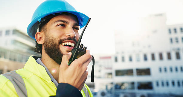 istock Construction site, radio and man with engineering, smile and inspection with quality control. Helmet, feedback and person with architecture, conversation and property renovation with safety check 2228476361