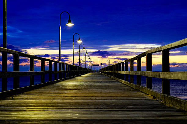istock A pier stretches into the distance, lined with lights under a deep blue night sky. Sun and clouds at dawn on the Baltic Sea beach of 18586 Göhren, Rügen Island 2228478128