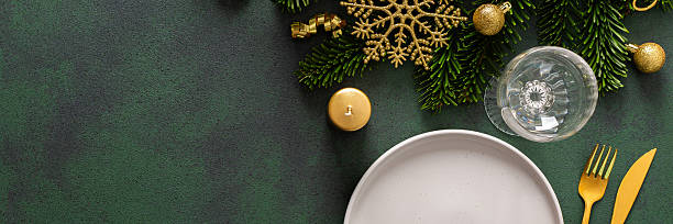 istock A Christmas table setting with an empty plate and cutlery on a green background. Spruse branches and golden tree decorations add elegance and festive cheer to the scene, banner 2228478454