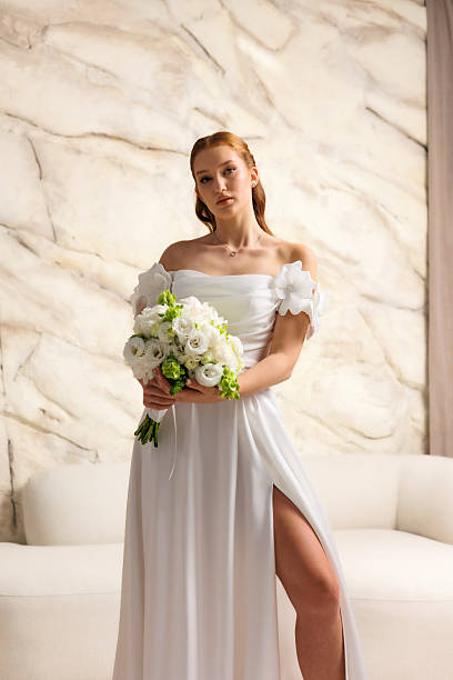 istock Bride wearing elegant white dress poses with bouquet in modern setting during wedding preparation 2228480158