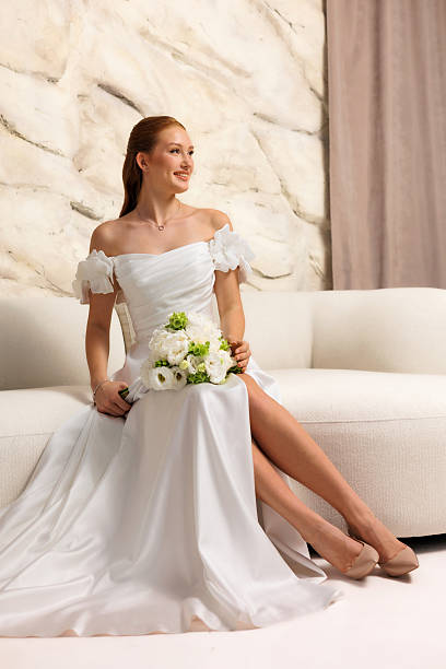 istock Bridal preparation in elegant setting with bride holding bouquet on a couch 2228481181