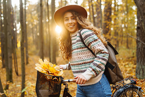 istock Cheerful woman riding a bicycle through a quiet autumn forest. 2228482644