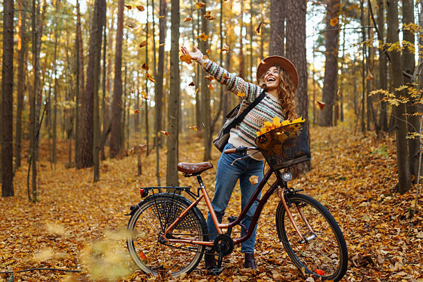 istock Cheerful woman riding a bicycle through a quiet autumn forest. 2228482662