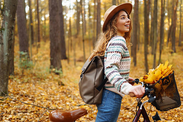 istock Cheerful woman riding a bicycle through a quiet autumn forest. 2228482664