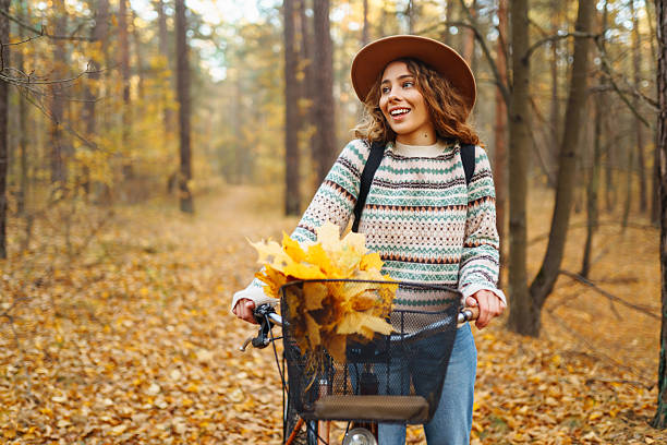 istock Cheerful woman riding a bicycle through a quiet autumn forest. 2228482675