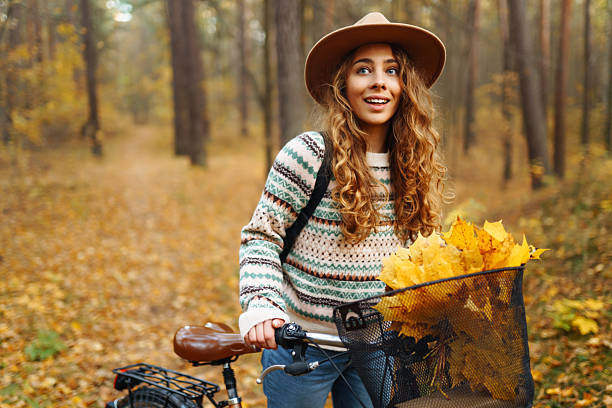istock Cheerful woman riding a bicycle through a quiet autumn forest. 2228482686
