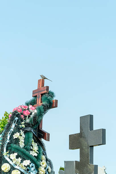 istock A tranquil wagtail perched on a memorial cross symbolizing hope and remembrance surrounded by vibrant flowers reflecting the beauty of life. Flowers on a grave. 2228482870