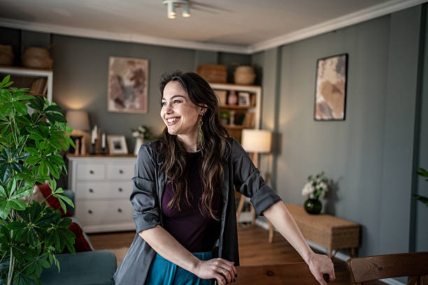 istock Young woman smiling and leaning on a table in her modern apartment 2228483072