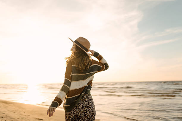 istock Joyful woman in hat having fun and walking on sunny beach. 2228483559