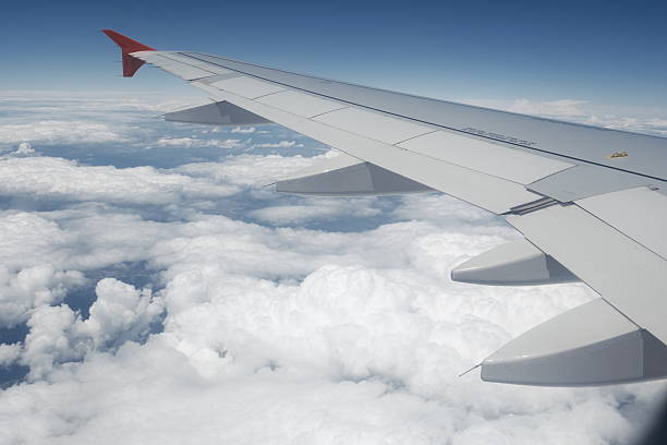 istock Airplane wing view above the clouds on a clear blue sky 2228485507