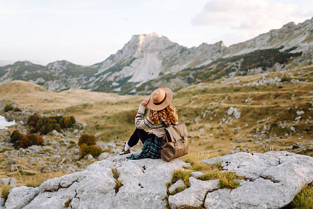 istock Happy female hiker in hat and authentic sweater with backpack enjoying mountain landscape on mountain trail. 2228486974