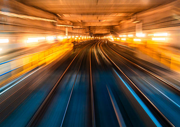Long exposure shot depicting the blurred motion of railroad tracks as viewed from a passenger train as it speeds through the city.