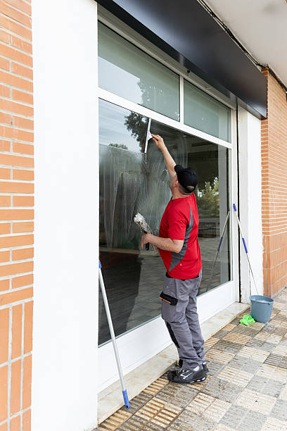 istock Professional window cleaner using squeegee to wash storefront glass 2228490309