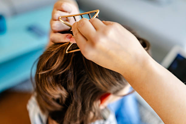 istock Young woman styling her hair indoors while using a hair accessory in a cozy setting 2228492443