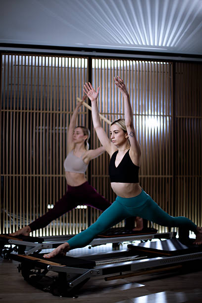 istock Two individuals practicing workout routines on reformer pilates machines in a modern studio during an evening session 2228495801