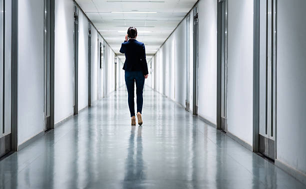 istock Woman walking and using mobile phone in a corridor 2228500493
