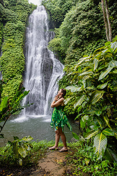 istock Woman standing near the refreshing waterfall on Bali 2228500731