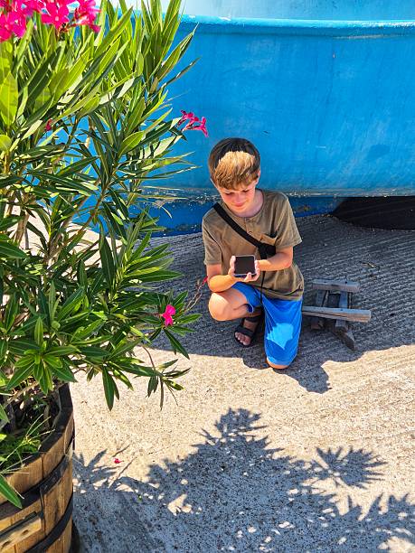 Teenage boy nature photographer taking photos with old analog vintage camera in nature. He is looking for rare birds and plants and photographing them.