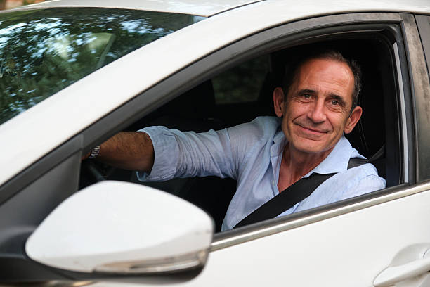 istock Mature man driving a car and smiling at camera 2228508248
