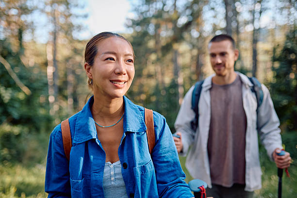 istock Hikers walking in forest using trekking poles, enjoying nature and smiling 2228509115