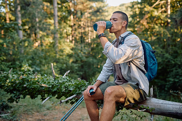 istock Hiker drinking water in forest during trekking excursion 2228511956