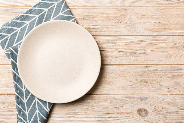 istock Top view on colored background empty round white plate on tablecloth for food. Empty dish on napkin with space for your design 2228513131