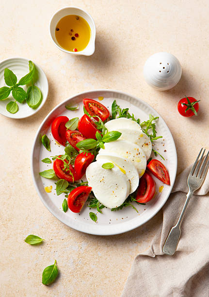 Caprese salad with tomatoes, mozzarella cheese and fresh basil. Beige background. Top view.