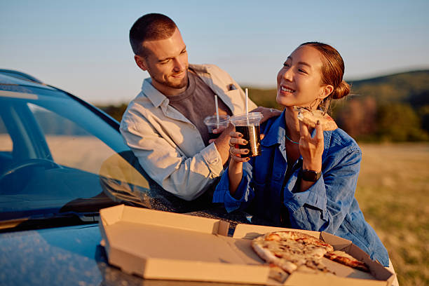istock Couple enjoying pizza and drinks during road trip at sunset 2228517316