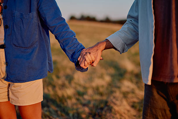 istock Senior couple holding hands in field at sunset 2228517545