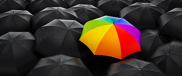 istock Crowd of black umbrellas with one unique rainbow colored umbrella 2228518539