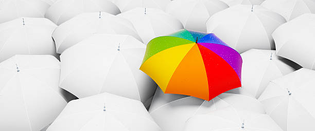 istock Crowd of white umbrellas with one unique rainbow colored umbrella 2228518540