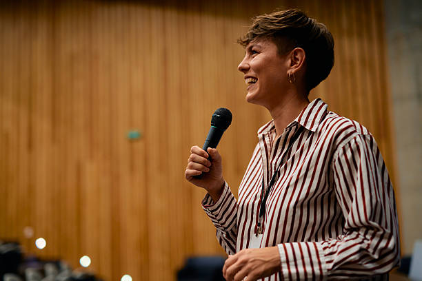 istock Smiling speaker with microphone talking to audience during a conference 2228519622