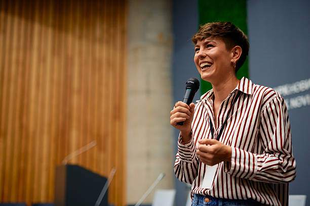istock Young businesswoman laughing while speaking at a conference using a microphone 2228519625