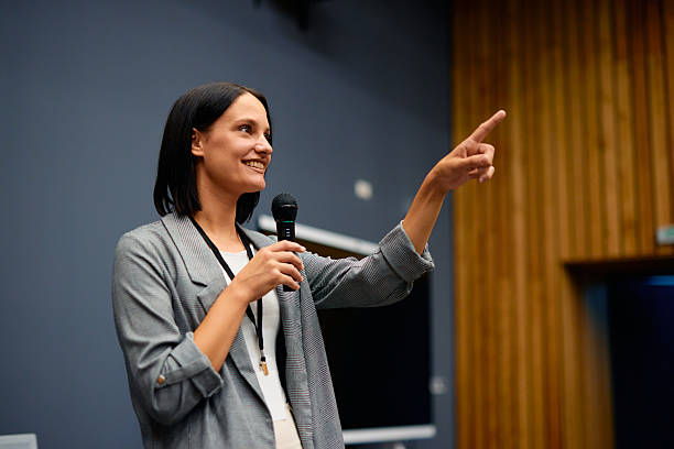 istock Businesswoman pointing with finger while speaking on microphone at conference 2228519692