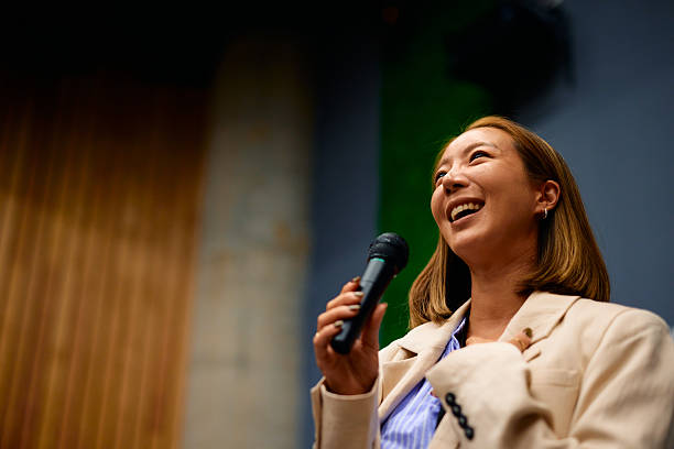 istock Young businesswoman laughing while speaking into a microphone during a conference 2228519719