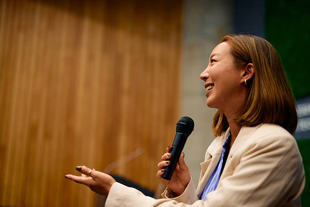 istock Businesswoman smiling and speaking with microphone at conference 2228519735