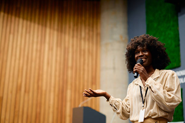 istock Young woman giving a speech holding a microphone 2228519745