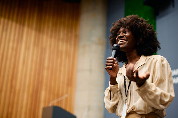 istock Young woman giving a speech holding a microphone and smiling 2228519750
