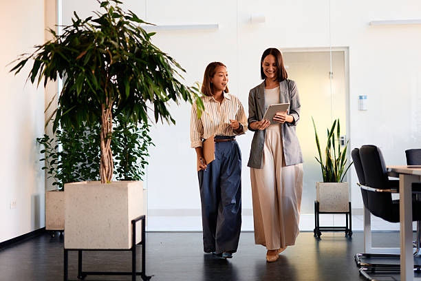 istock Two businesswomen walking and talking in modern office 2228519881