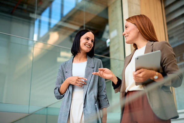 istock Two businesswomen talking and smiling in a modern office building 2228519917