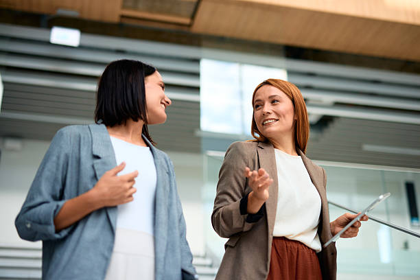 istock Two businesswomen talking and smiling in modern office building 2228519943