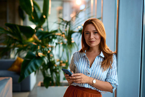 istock Confident businesswoman holding smartphone, looking at camera 2228522347