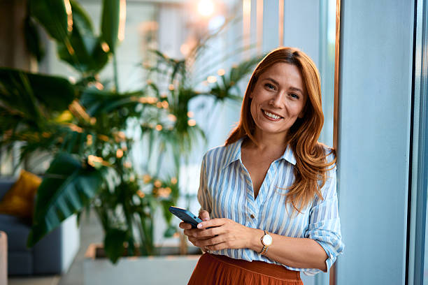 istock Businesswoman smiling and using smartphone in modern office 2228522362