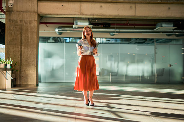 istock Businesswoman walking in modern office building using smartphone 2228523230