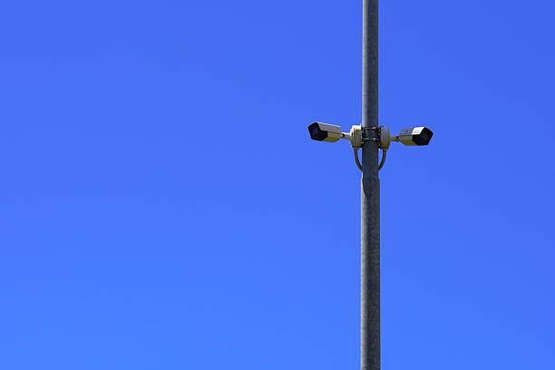 istock Metal pole with two CCTV cameras facing opposite directions against a clear blue sky - plenty of space for advertising, perfect for security or technology themes 2228530288