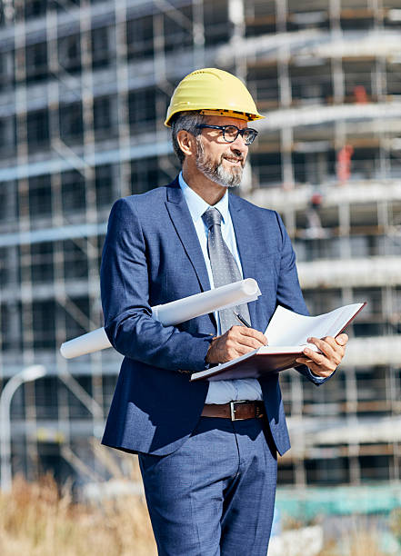 istock senior businessman architect helmet construction site building architecture writing notebook protective workwear blueprint plan 2228531175